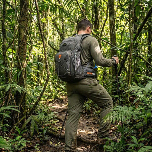 Stealth Pro Hydration Backpack - 15 Litres - Charcoal Grey being used on a hiking trail in a lush jungle.
